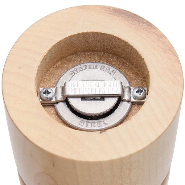 A close-up of a wooden pepper mill with a metal button.