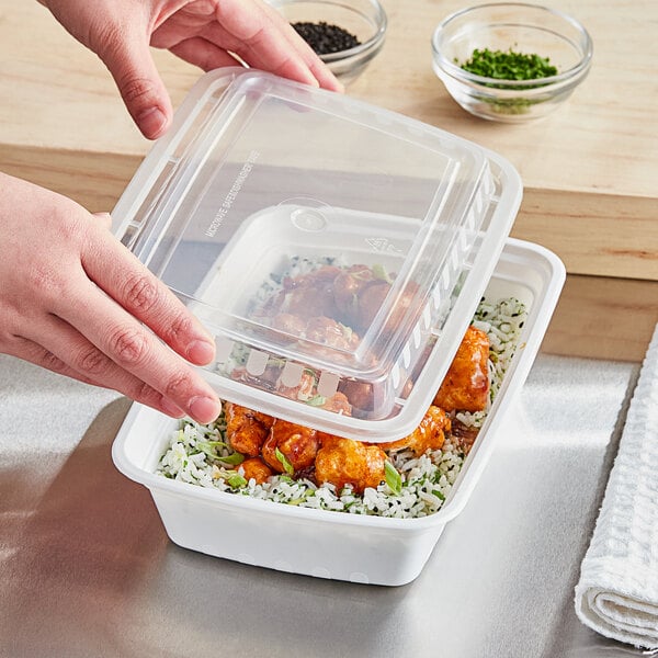 A hand holding a Choice white rectangular plastic container with food inside.