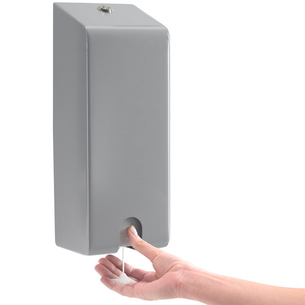 A person's hand using a GOJO ADX-12 silver security closure on a soap dispenser.