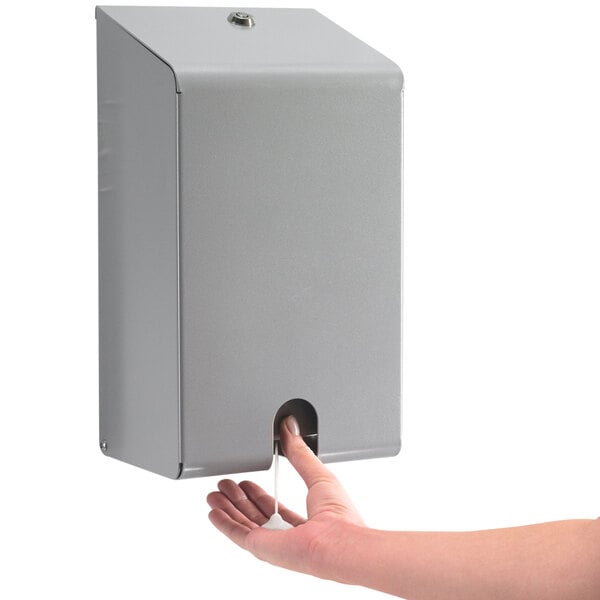 A close-up of a silver security enclosure for a GOJO hand sanitizer dispenser.