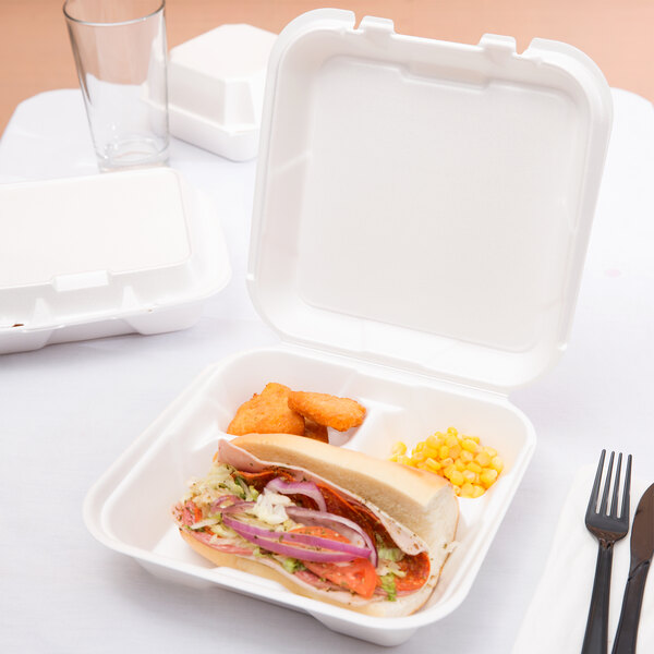 A sandwich with meat and vegetables and a fork in a white Genpak foam container.