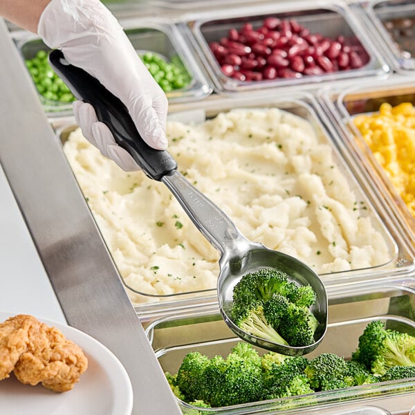 A person using a Vollrath black solid oval spoodle to serve broccoli and mashed potatoes.