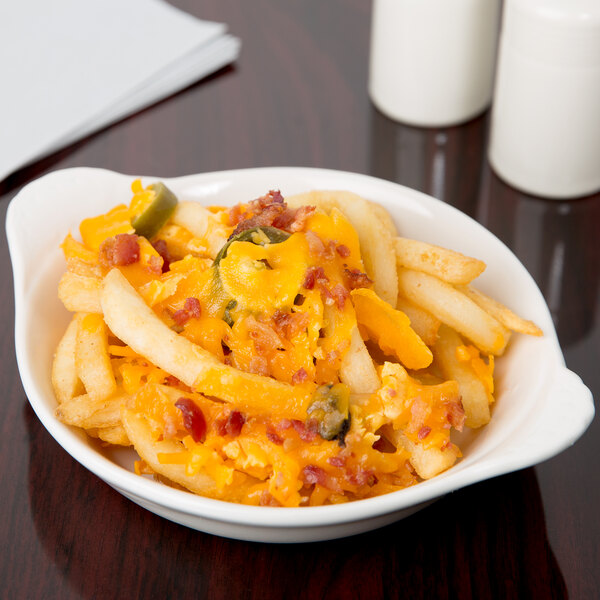 A CAC bone white stoneware shirred egg dish filled with french fries, cheese, and jalapenos.