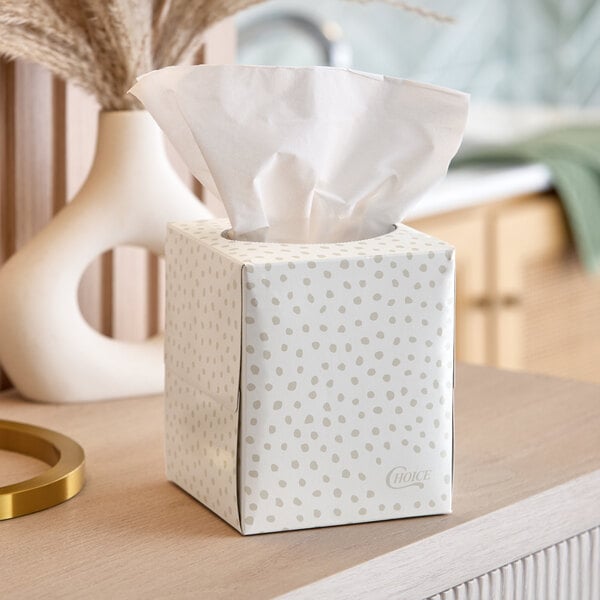 A cube-shaped box of facial tissues with a light polka dot pattern.