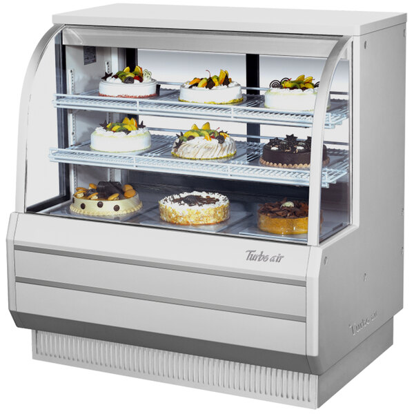 A white Turbo Air dry bakery display case with cakes inside.