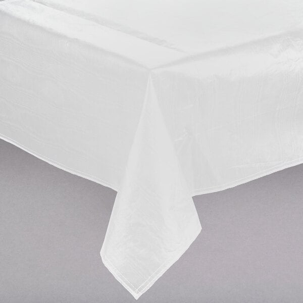 A close-up of a white Intedge vinyl table cover with flannel back on a table.