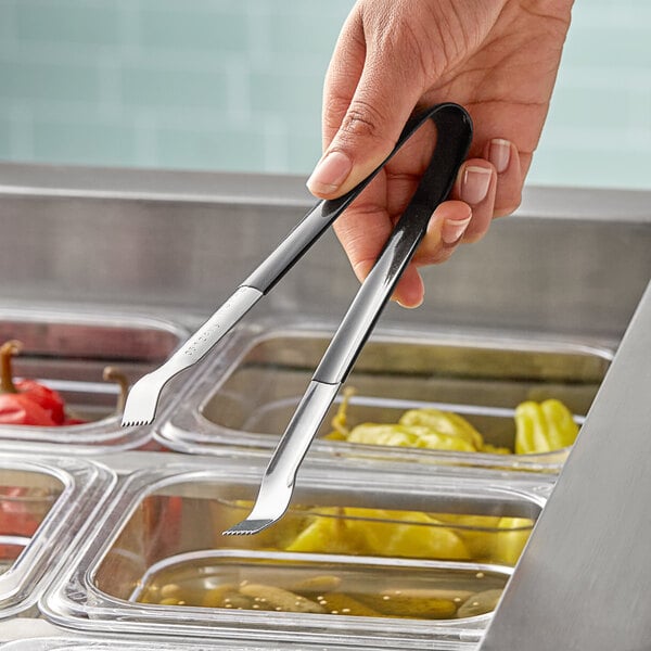 A person using Vollrath Kool-Touch Pom Tongs to serve food from a tray.