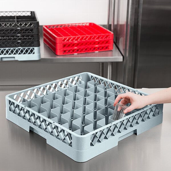 A hand holding a glass in a gray dish rack.