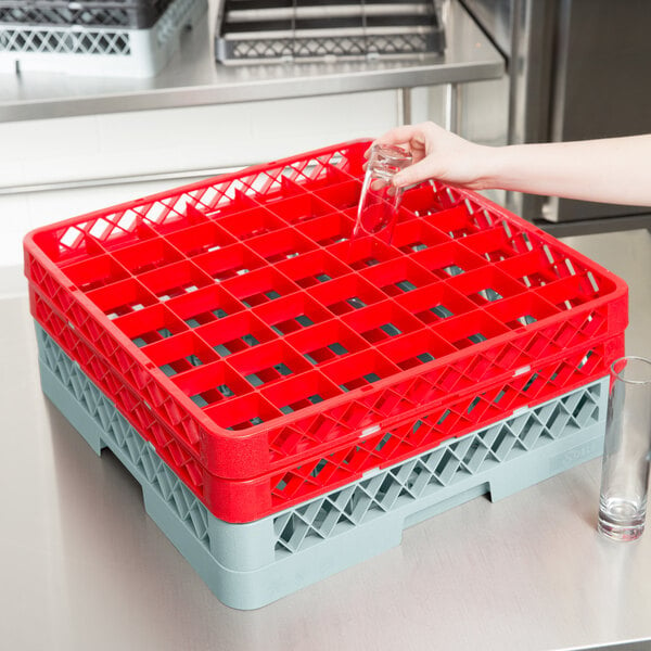 A hand holding a glass in a red and grey plastic Noble Products glass rack.