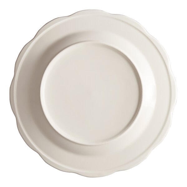 An ivory Acopa stoneware plate with a scalloped edge.