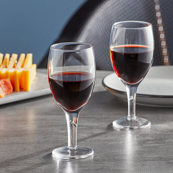 Two Anchor Hocking Perfect Portions wine taster glasses filled with red wine on a table.