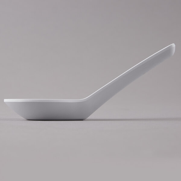 A close-up of a GET white melamine soup spoon with a white handle.