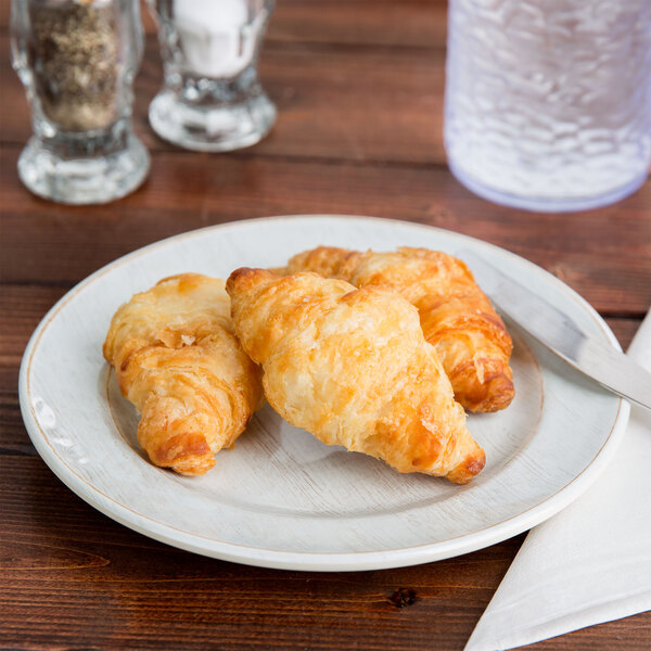 A Carlisle melamine bread and butter plate with two croissants on it.