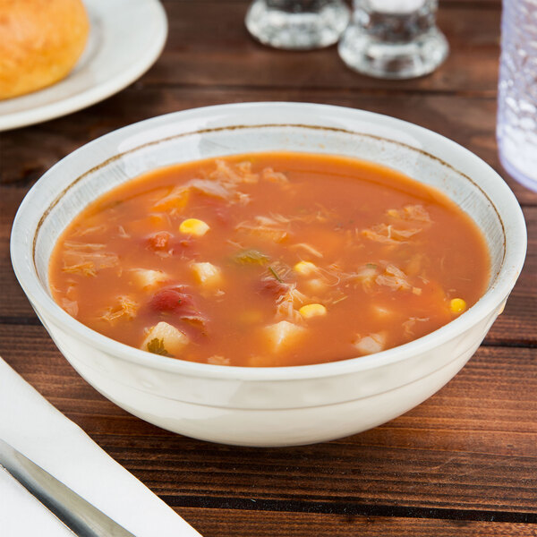 A Carlisle Grove melamine bowl filled with soup, corn, and beans on a table.
