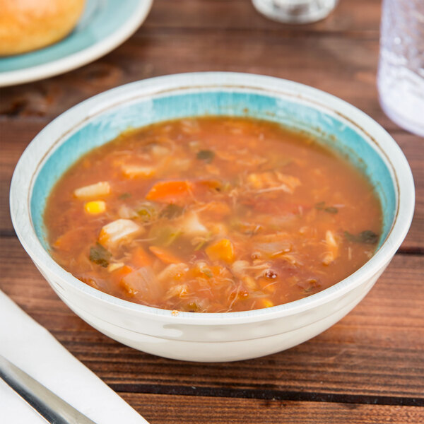 A Carlisle Grove melamine bowl filled with soup on a table.