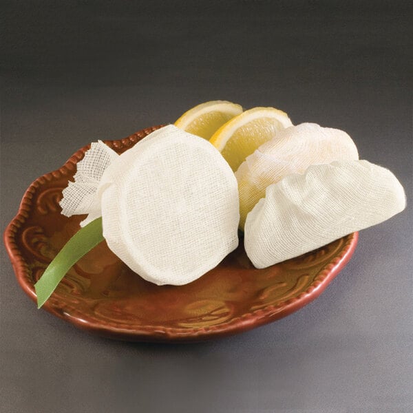 A plate with a lemon wedge in a white gauze bag.