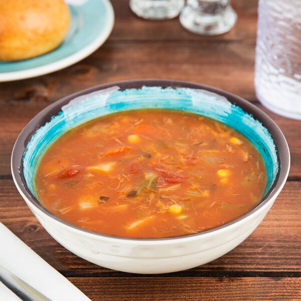 A Carlisle aqua melamine bowl filled with soup on a table with a spoon.