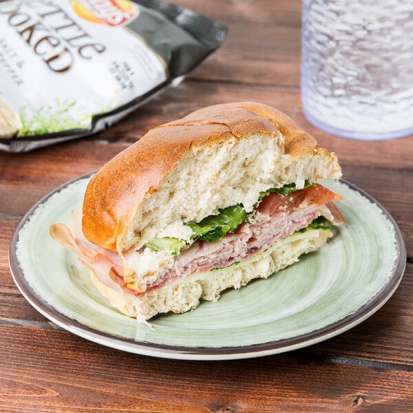 A sandwich on a Carlisle jade melamine bread and butter plate next to a bag of chips.