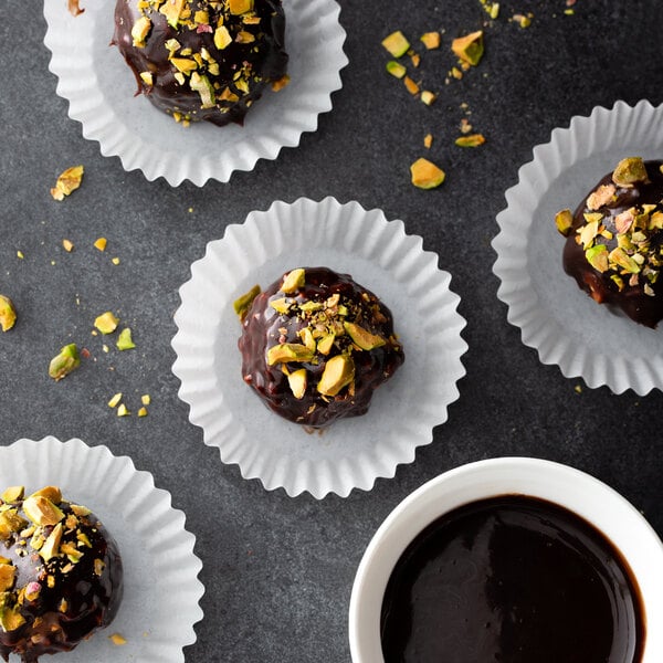 A group of chocolate candies in white fluted mini baking cups with a cup of hot chocolate.