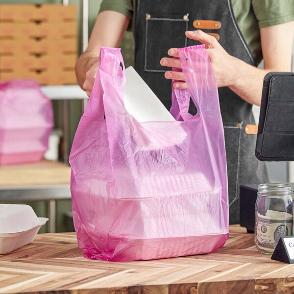 A person holding a purple plastic bag with a white container inside.