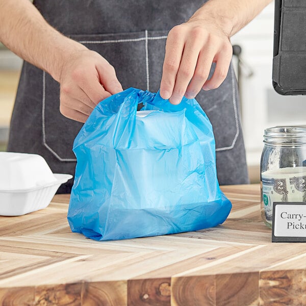 A man holding a blue Choice medium-duty T-shirt bag with a white object inside.