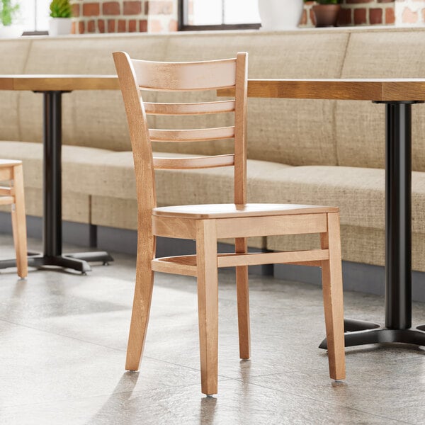A Lancaster Table & Seating wooden chair with a natural wood seat in a restaurant.