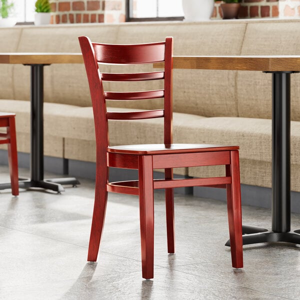 A Lancaster Table & Seating mahogany wood ladder back chair with mahogany wood seat in a restaurant.