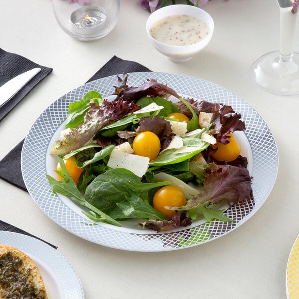 A Visions white plastic plate with salad, tomatoes, and cheese.