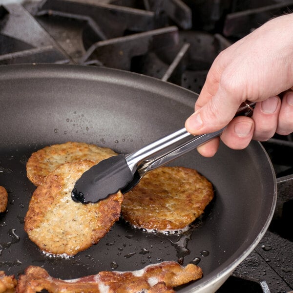 Person using silicone tongs to flip a sausage patty