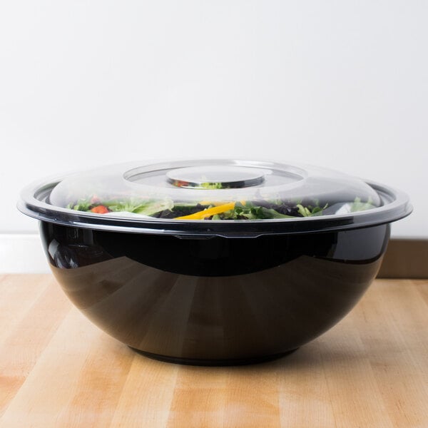A clear plastic bowl with a clear plastic lid on top of a wooden table.