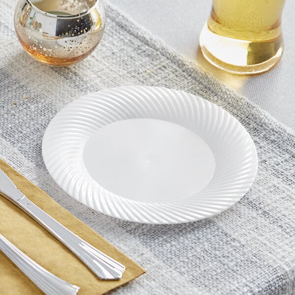 A close-up of a Visions white plastic plate with a fork and knife on it.