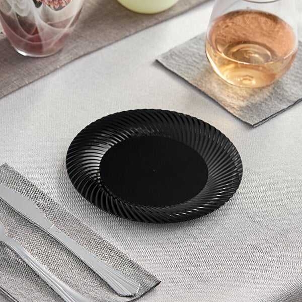 A Visions black plastic plate with a knife on a table.