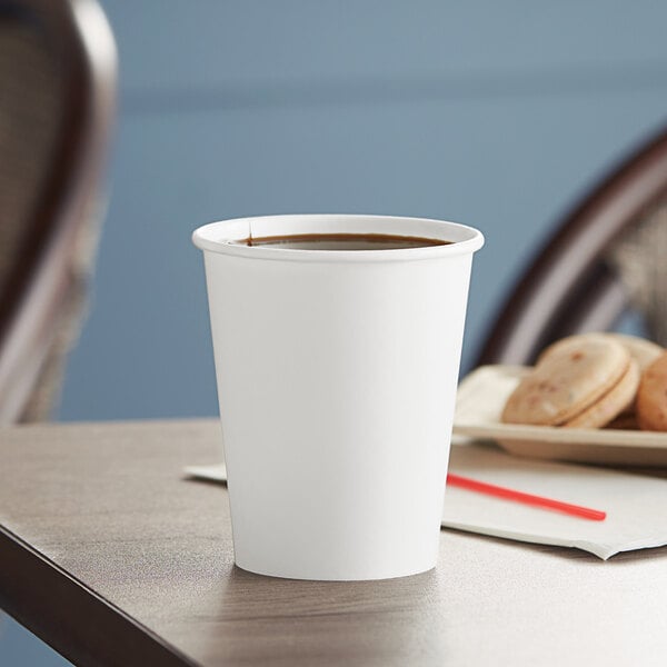 A close-up of a Solo white paper hot cup on a table with coffee inside.