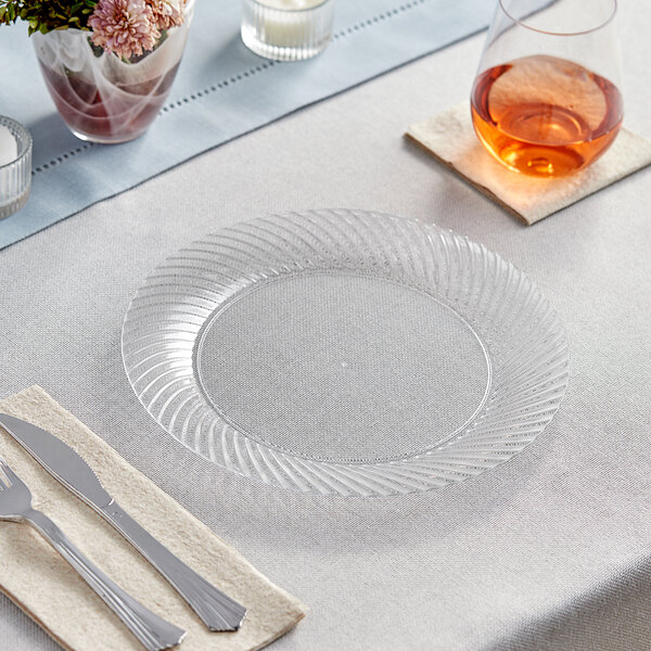 A Visions clear plastic plate with silverware on a table.