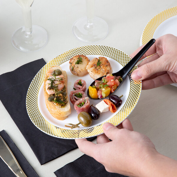 A hand holding a Visions white plastic plate with food on it.