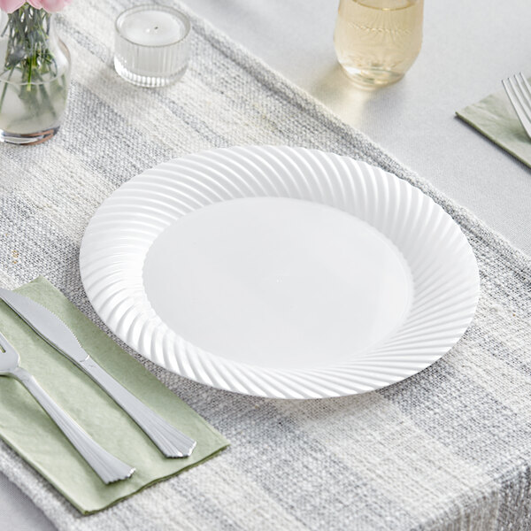 A Visions white plastic plate with a knife and fork on it.