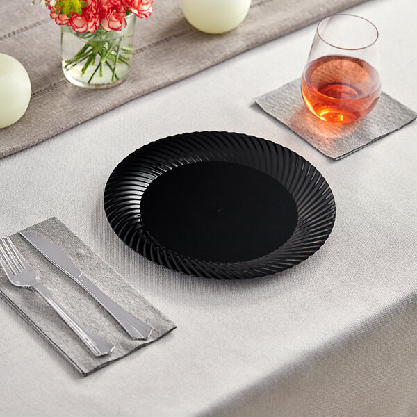 A Visions black plastic plate on a table with a fork and knife