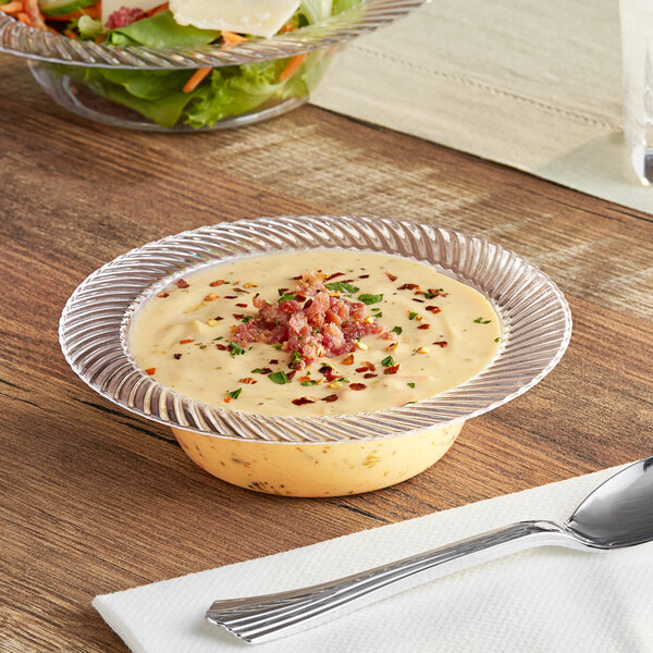 A clear plastic bowl of soup with bacon and spices next to a Visions Wave clear plastic bowl of food.