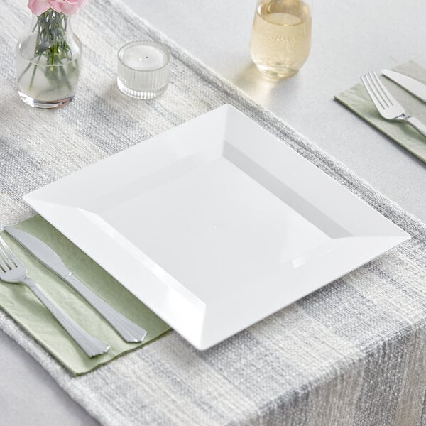 A white square Visions Florence plastic plate with a fork and knife on a napkin.