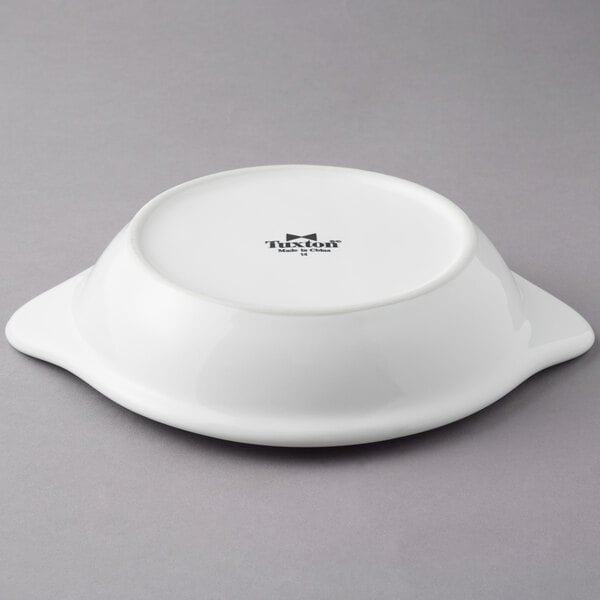 A white Tuxton round shirred egg dish with black text.