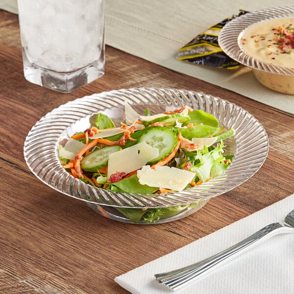 A bowl of salad on a table in a clear plastic bowl.