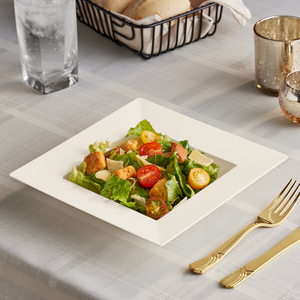A square Visions plastic bowl filled with salad on a table.