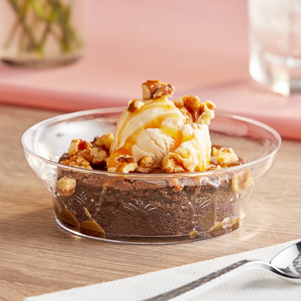 A chocolate brownie with ice cream and caramel in a clear bowl.