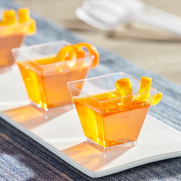 A tray of Visions clear square plastic shot glasses filled with orange liquid.