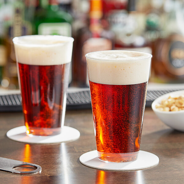 Two Choice clear plastic disposable tumblers filled with beer on a table.