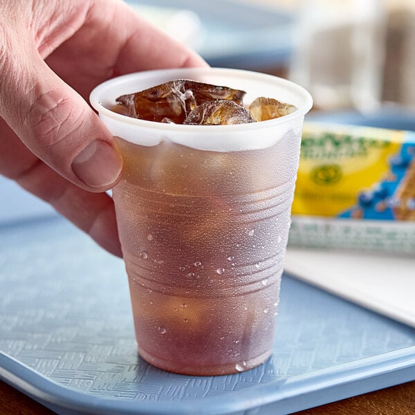 A hand holding a Dart translucent plastic cold cup with ice in it.