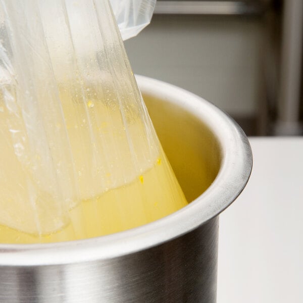 A plastic bag with yellow liquid in a stainless steel container.