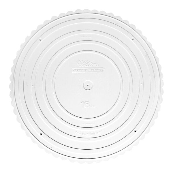 A white circular Wilton cake separator plate with a scalloped edge.