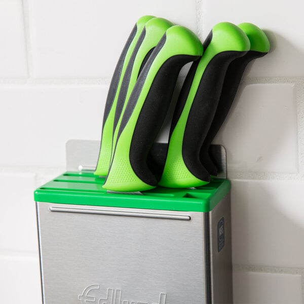 A group of knives in a green and black Edlund knife rack.