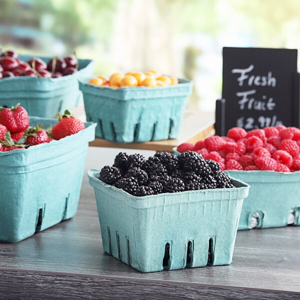 A table with several green molded pulp containers filled with berries.